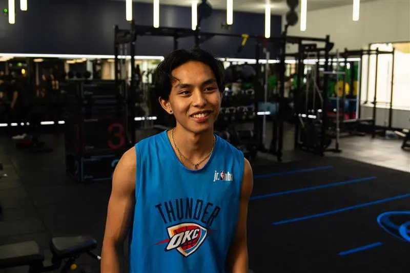 Student smiling in the gym infront of the rig.