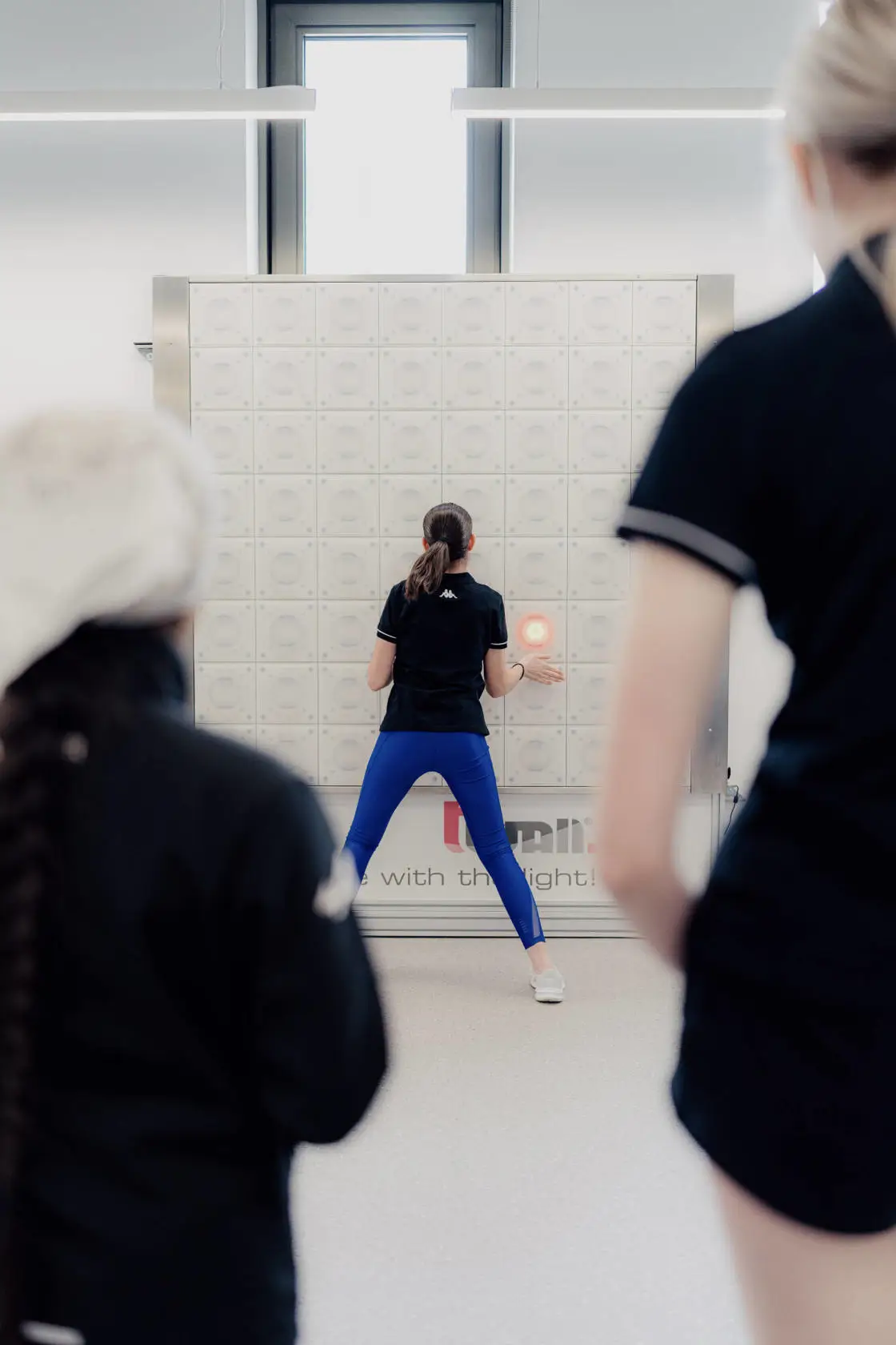 Girl testing reactions in front of a reaction wall, hitting lights as they light-up