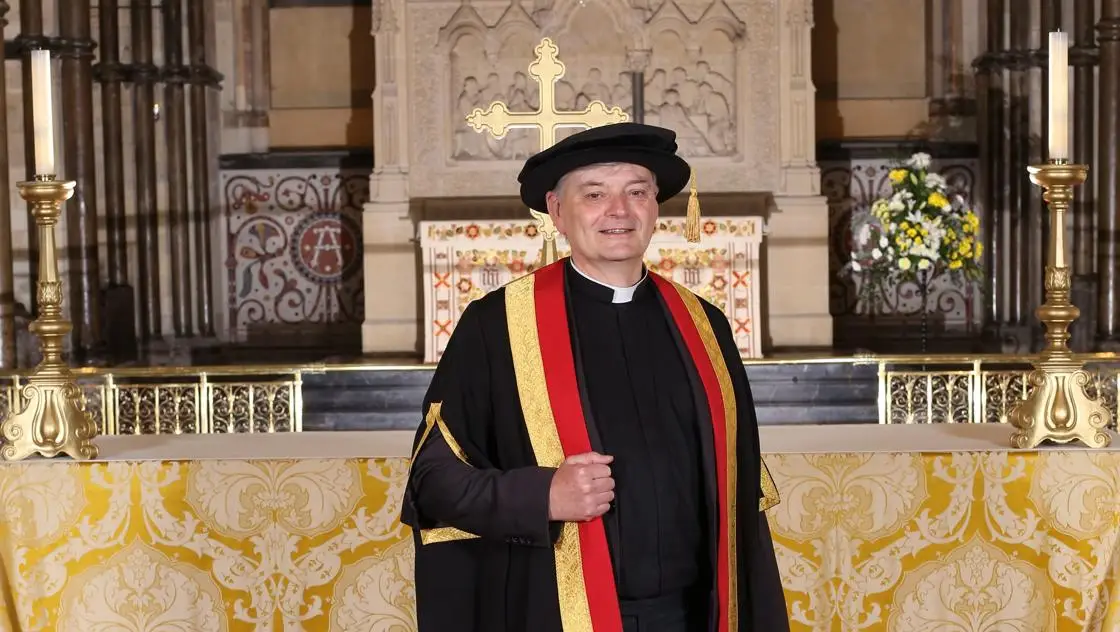 The Dean of Rochester standing in front of the altar in Rochester Cathedral. 