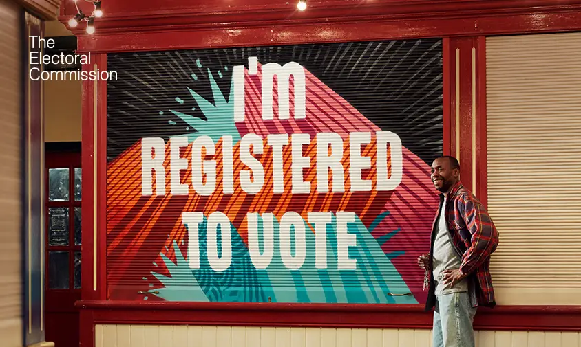 Man stood in front of a sign that says 'I'm registered to vote".